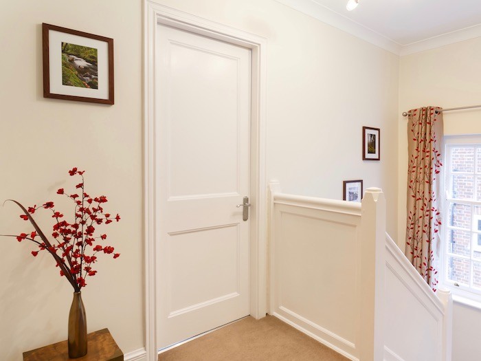 Interior door painted white. Bright red flowers in a vase.